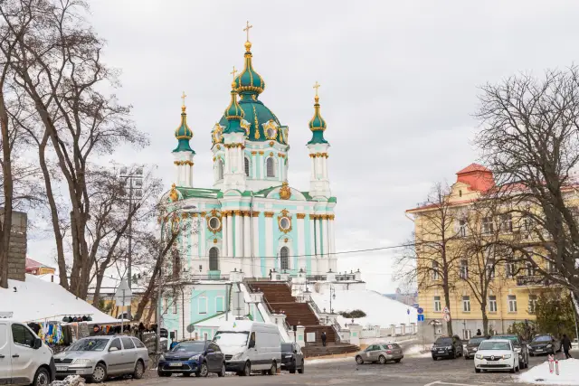 Андріївська церква з бірюзовим фасадом і золотим декором над засніженим узвозом.