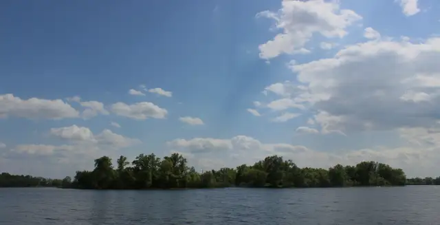 Низький деревний силует Козачого острова над широкою водою Дніпра під літнім небом.