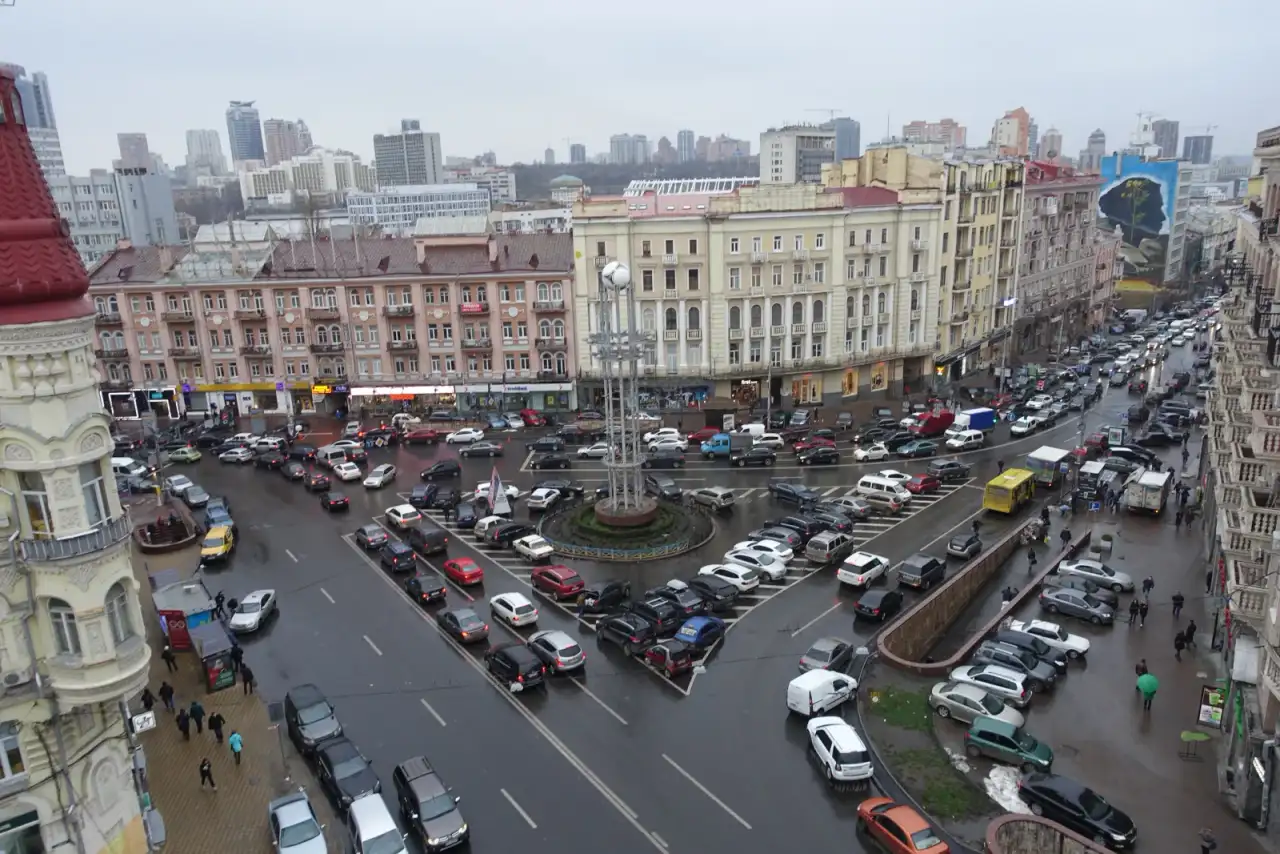 Панорама площі Українських Героїв із транспортним острівцем, щільним рухом і фасадами в грудні 2017 року